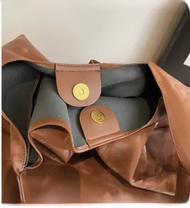 Dettaglio della chiusura magnetica in oro lucido sulla borsa a secchiello in pelle marrone