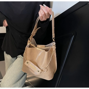 Detail of camel bucket bag featuring gold chain link and adjustable shoulder strap