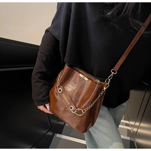 Detail of brown vintage bucket bag featuring gold chain and a fashion leather pendant