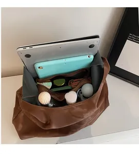 Interno spazioso della borsa tote marrone con laptop e vari oggetti di uso quotidiano