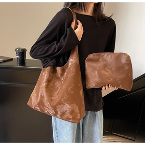 Dettaglio di un set di borse tote in pelle marrone con borsa a spalla grande e pochette piccola