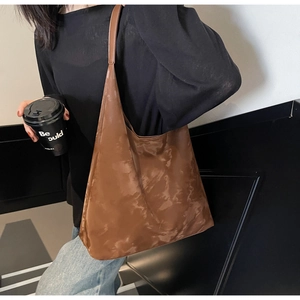 Vista dettagliata della borsa a spalla grande marrone lucida su una modella