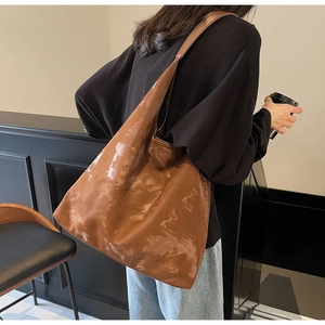 Dettaglio della capiente borsa tote in pelle lucida color caramello a spalla