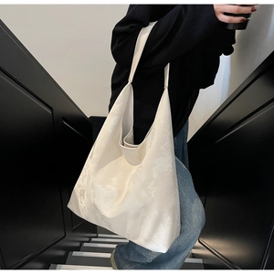 Dettaglio della borsa shopper minimalista color crema con motivo marmorizzato e tracolla