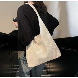 Grande borsa tote crema con motivo marmorizzato indossata da una modella in interni