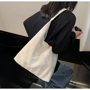 Vista laterale di una borsa tote oversize beige con trama marmorea indossata da modella