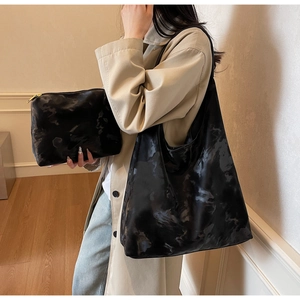 Dettaglio della borsa tote nera con stampa nuvole e pochette abbinata su un trench