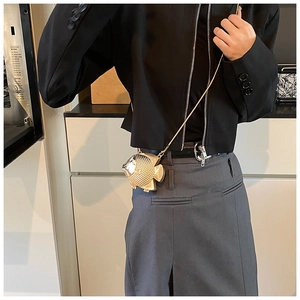 Detail of fish-shaped gold metal mini bag with scale texture on a shoulder chain