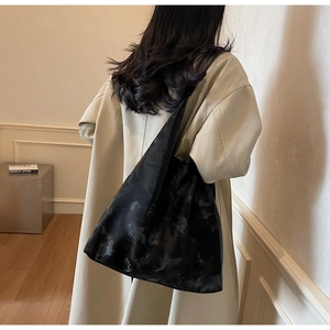 Dettaglio della borsa shopper nera marmorizzata con texture in seta su cappotto bianco