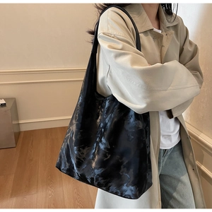 Dettaglio di borsa tote nera minimalista con trama marmorizzata e finitura vintage