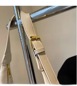 Detail of adjustable cream shoulder strap with polished gold buckle and premium stitching
