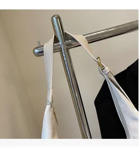 Close-up of beige tote bag wide strap with metal D-ring buckle on hanging display