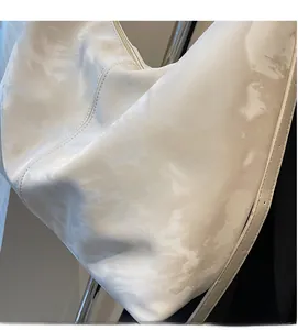 Close-up of cream textured tote bag showing soft cloud pattern and premium zipper detail