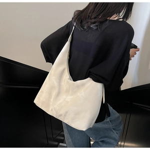 Rear view of a model wearing a modern white glossy hobo bag with large storage capacity