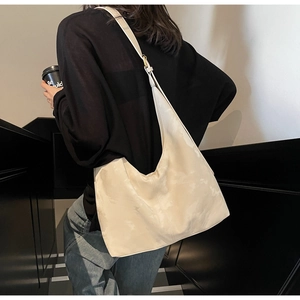 Minimalist beige hobo bag detail showing soft leather texture and adjustable strap on shoulder