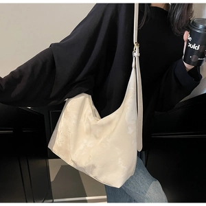 Detail of cream hobo bag showing soft leather texture and adjustable strap on model