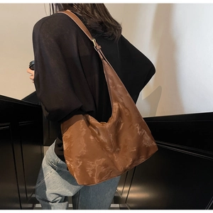 Detail of a large brown tote bag in moire textured glossy leather with an adjustable strap