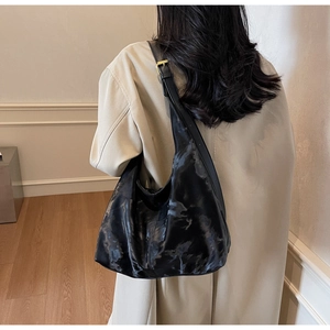 Hobo bag detail featuring black textured synthetic leather and a gold metal buckle strap
