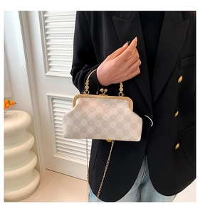 Elegant beige shell bag with chain strap styled on a black suit in a minimalist setting