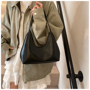 Elegante borsa sottobraccio in vernice nera con finitura lucida in una posa street style
