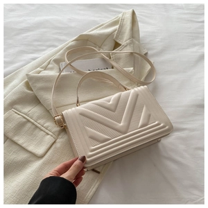 Close-up of creamy beige small square bag featuring quilted V-shaped texture on PU leather