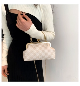 Detalle de bolso vintage con cadena dorada y estampado floral de cuadros en la modelo