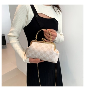 Detalle de bolso retro beige con diseño de cuadros florales y asa metálica dorada de lujo