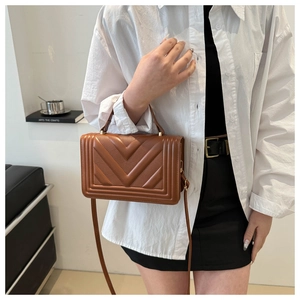 Brown quilted crossbody bag with chevron pattern shown on a model in a minimal setting