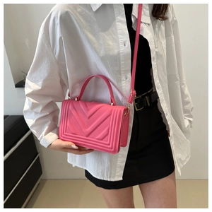 Detail of rose pink crossbody bag with V-shaped quilting worn by a model in soft light