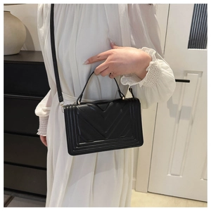 Close-up of black crossbody bag with V-shaped quilted pattern and multi-layered trim