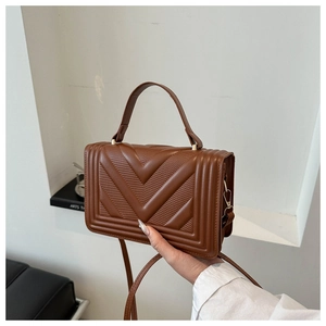 Detail of vintage brown leather handbag with V-shaped quilting and gold hardware