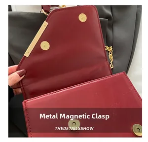 Macro shot of the golden magnetic snap and metal trim on this burgundy leather bag
