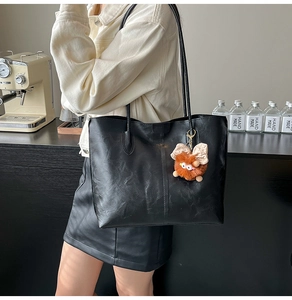 Détail d'un sac cabas en cuir PU noir texturé avec un joli pendentif en peluche marron