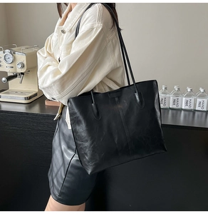 Détail d'un grand sac cabas noir avec de fines anses porté dans un décor rétro chic