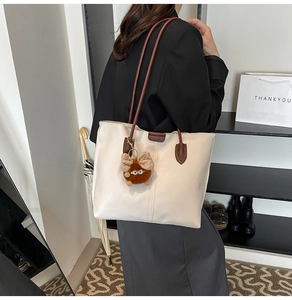 Détail du grand sac cabas crème minimaliste avec bandoulière marron et petit pendentif