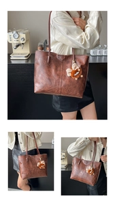 Détail d'un sac cabas vintage marron foncé avec pendentif en peluche et fines bandoulières