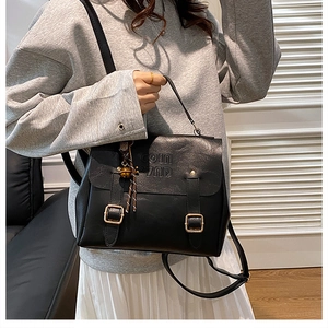Detail of black PU backpack featuring twin buckle straps and COIN embossed lettering