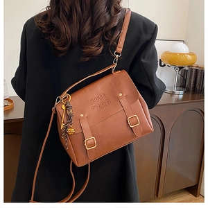 Brown vintage faux leather crossbody bag with retro belt buckles and metal pendant detail
