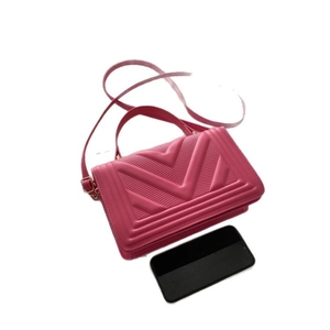 Pink chevron quilted handbag with top handle and gold hardware shown with a phone for scale