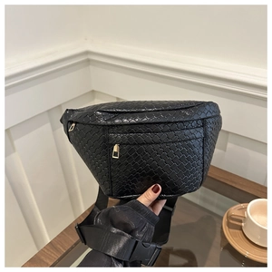 Detail of black woven chest bag featuring dual gold zippers and adjustable strap buckle