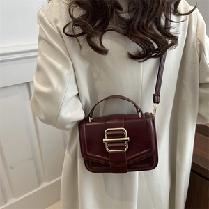 Retro burgundy leather handbag with gold metal clasp shown on model for daily crossbody use
