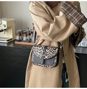 Detail of trendy leopard print saddle bag with gold metal buckle and black leather strap