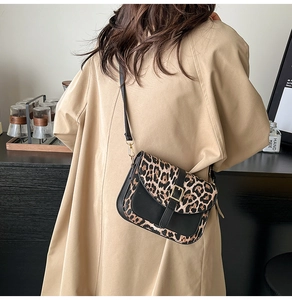 Borsa a tracolla leopardata con finiture in pelle nera e chiusura dorata su una modella