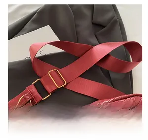 Dettaglio borsa a tracolla rossa intrecciata con cinghia regolabile e fibbie dorate