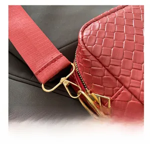 Dettaglio della pelle intrecciata rossa con gancio in metallo dorato e finiture della zip