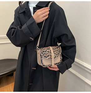 Detail of leopard print saddle bag with gold buckle on a stylish model in black coat