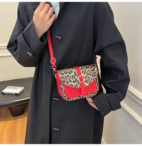 Chic leopard print and red leather crossbody bag worn with a stylish black trench coat