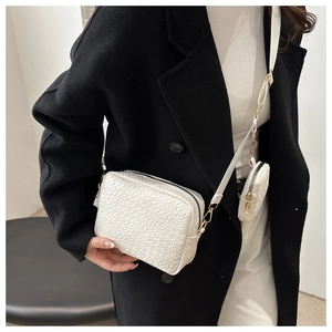 Detail of white textured crossbody bag with gold hardware and small detachable coin purse