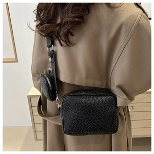 Detail of black woven crossbody bag featuring a golden zipper and a round mini coin purse