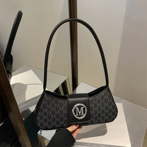 Detailed view of silver M metal buckle on a black monogram underarm bag with book decor